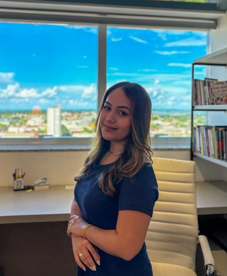 Giovana Tanaka, psicóloga clínica e do esporte, em seu consultório, com a vista da cidade ao fundo.